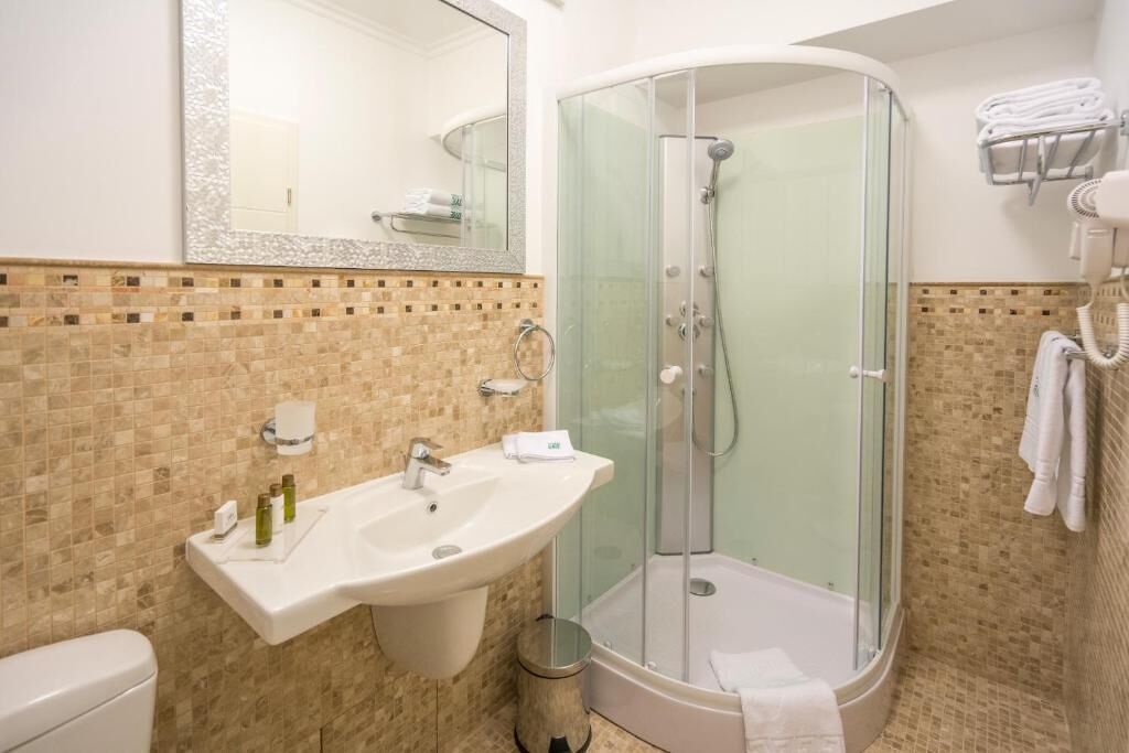A bathroom with a glass-enclosed shower, a sink with toiletries, and a towel rack.