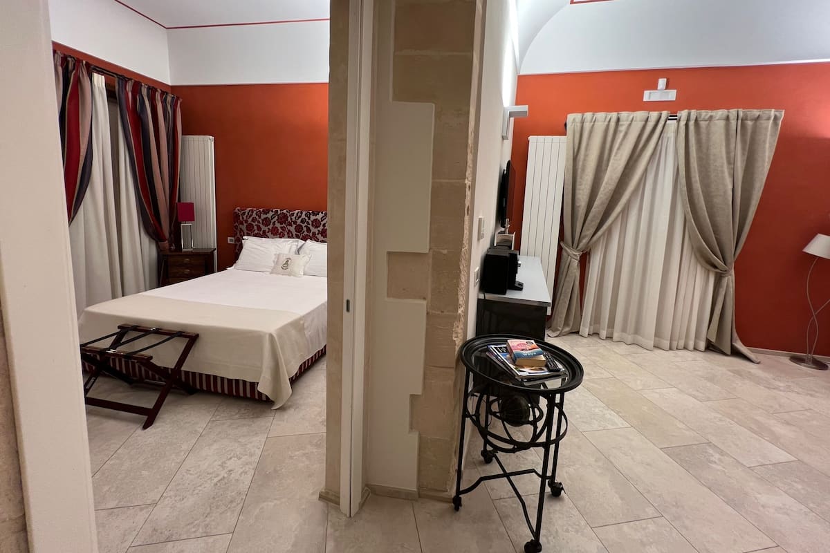 A hotel room with a bed, a small table with books, and a mirror.