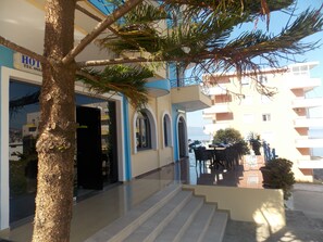 Entrada de hotel con una escalera que lleva al piso superior, zona de estar al aire libre y vista al mar.