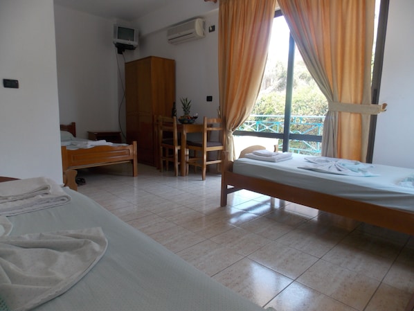 Une chambre d’hôtel avec deux lits, un bureau en bois, une chaise, une télévision et un climatiseur.