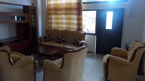 Uma sala de estar com sofá, duas poltronas, uma mesa de centro e um armário de madeira.