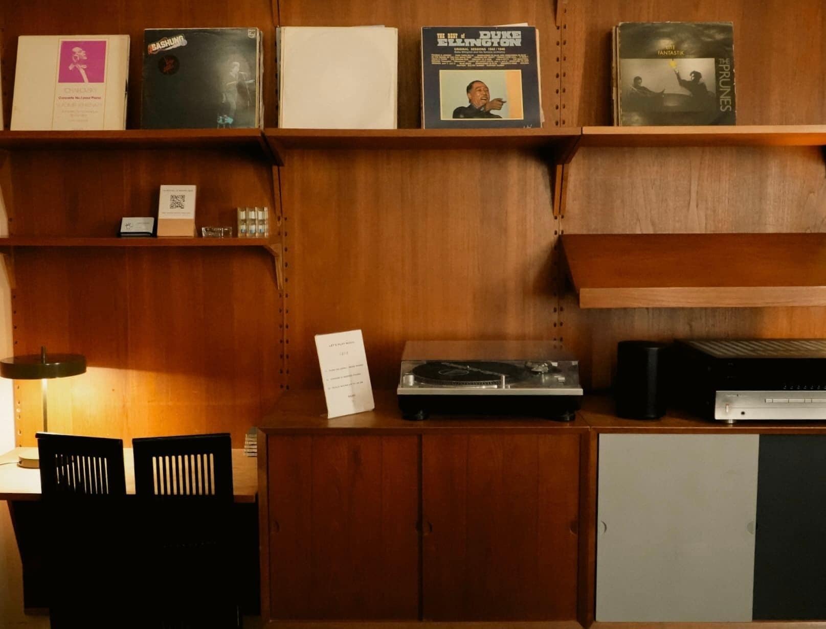 A wooden shelf with vinyl records, a turntable, and a cassette player.