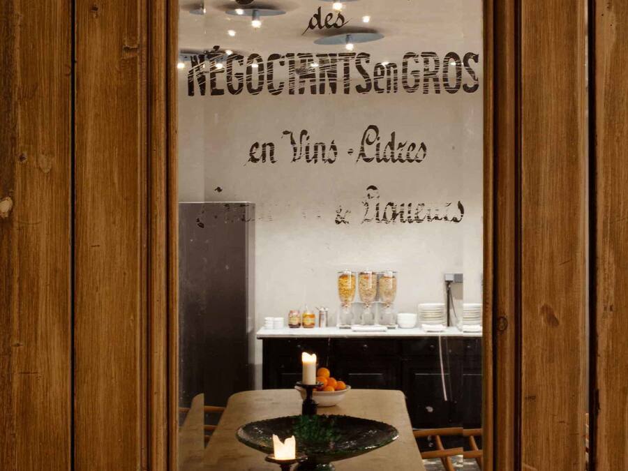 A wooden-framed mirror reflecting a restaurant interior with a candle on a table, a menu board, and a counter with food and drink items.