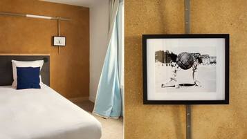 A hotel room with a bed, a framed picture on the wall, and a window with curtains.