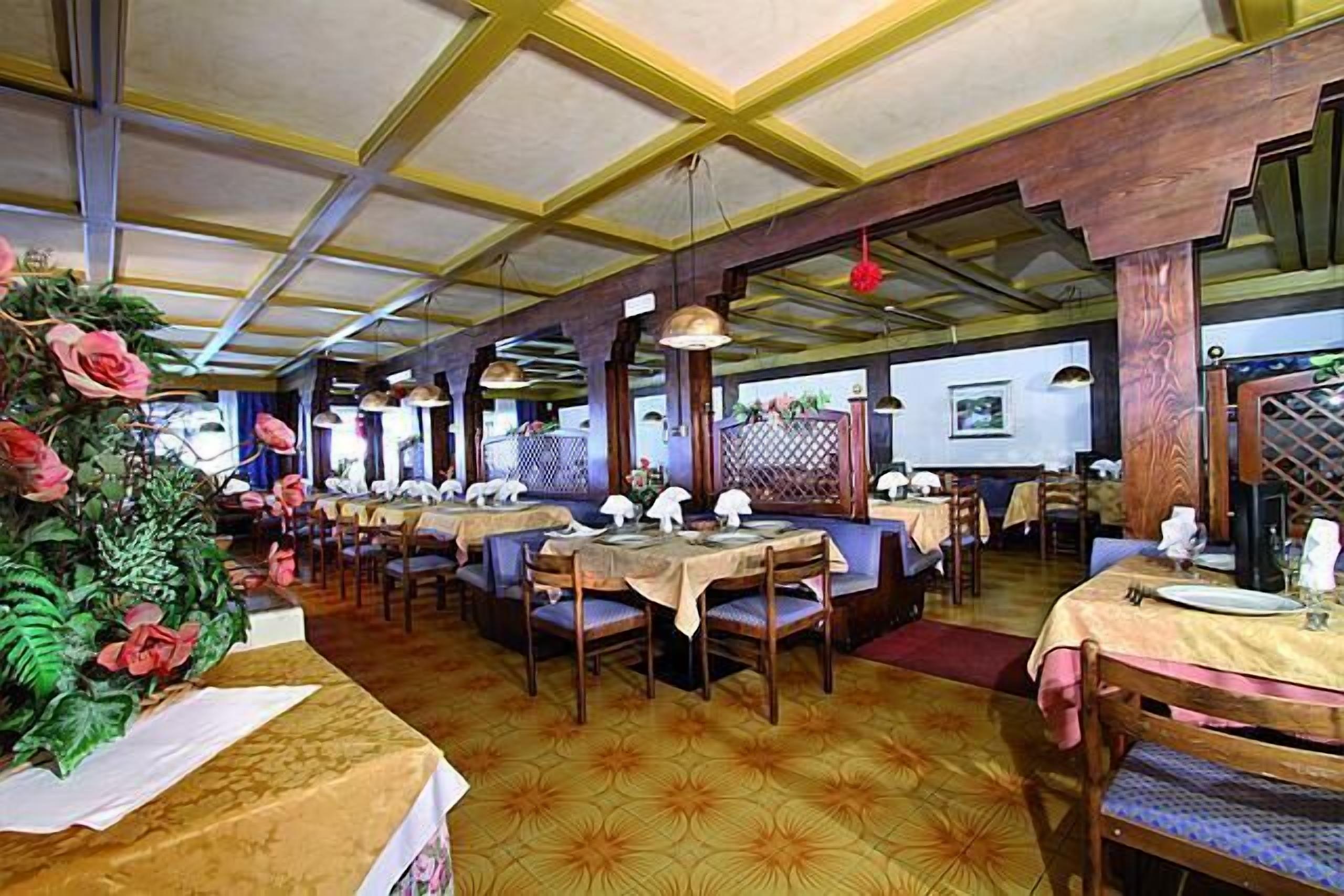 Un restaurante con varias mesas y cabinas, vigas de madera en el techo y un suelo con diseño.