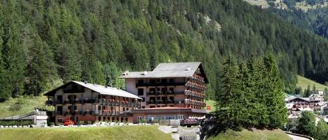 A multi-story hotel with a traditional Alpine architectural style, featuring balconies and a stone facade.