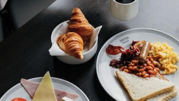 Ein Frühstückstisch mit Speisen, einer Kaffeetasse und einem Croissant.