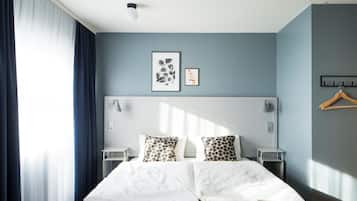 Habitación de hotel moderna con una cama grande, mesitas de noche, un aplique de pared y un perchero.