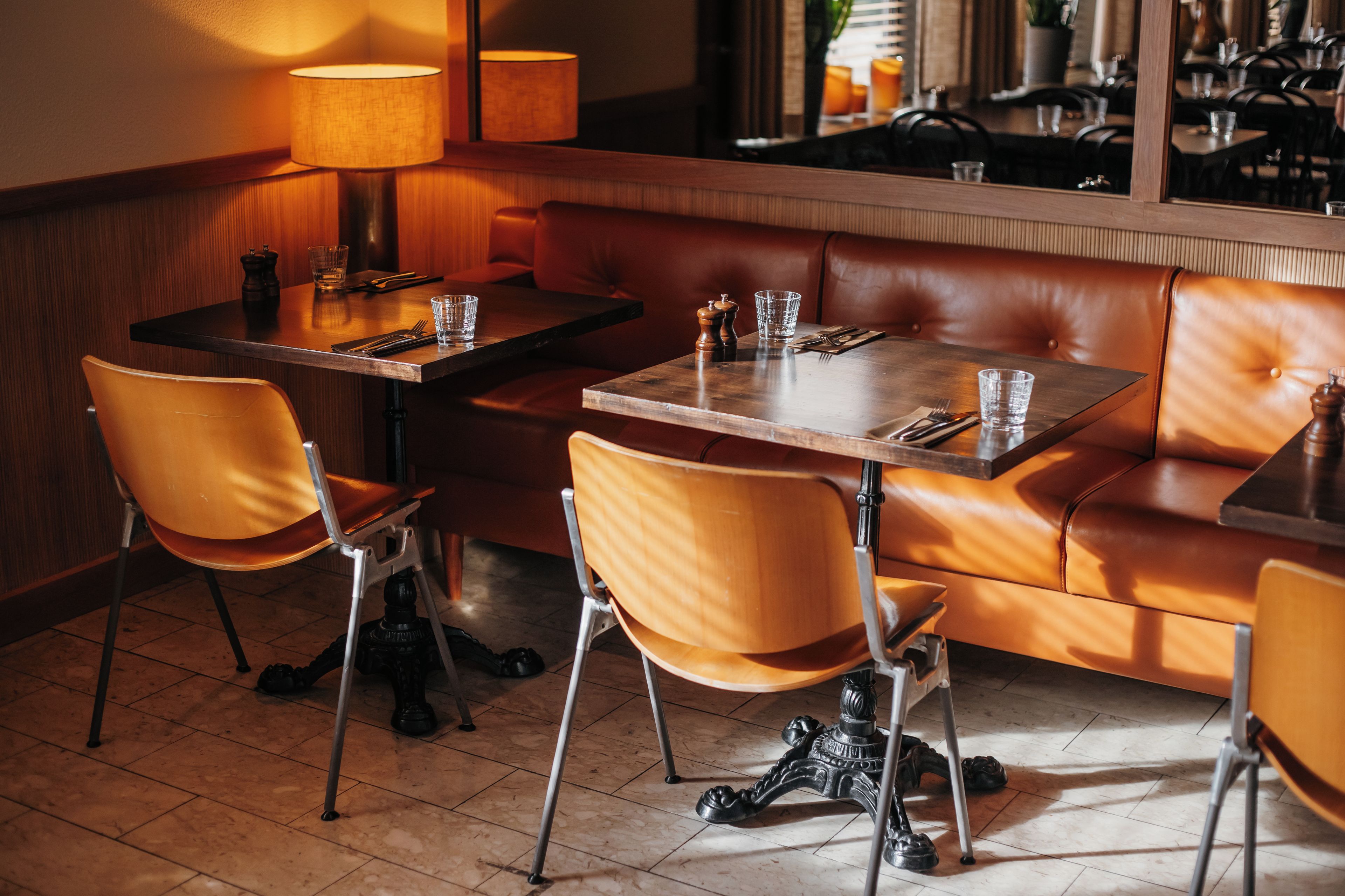A restaurant interior with leather booths, wooden tables, and chairs.