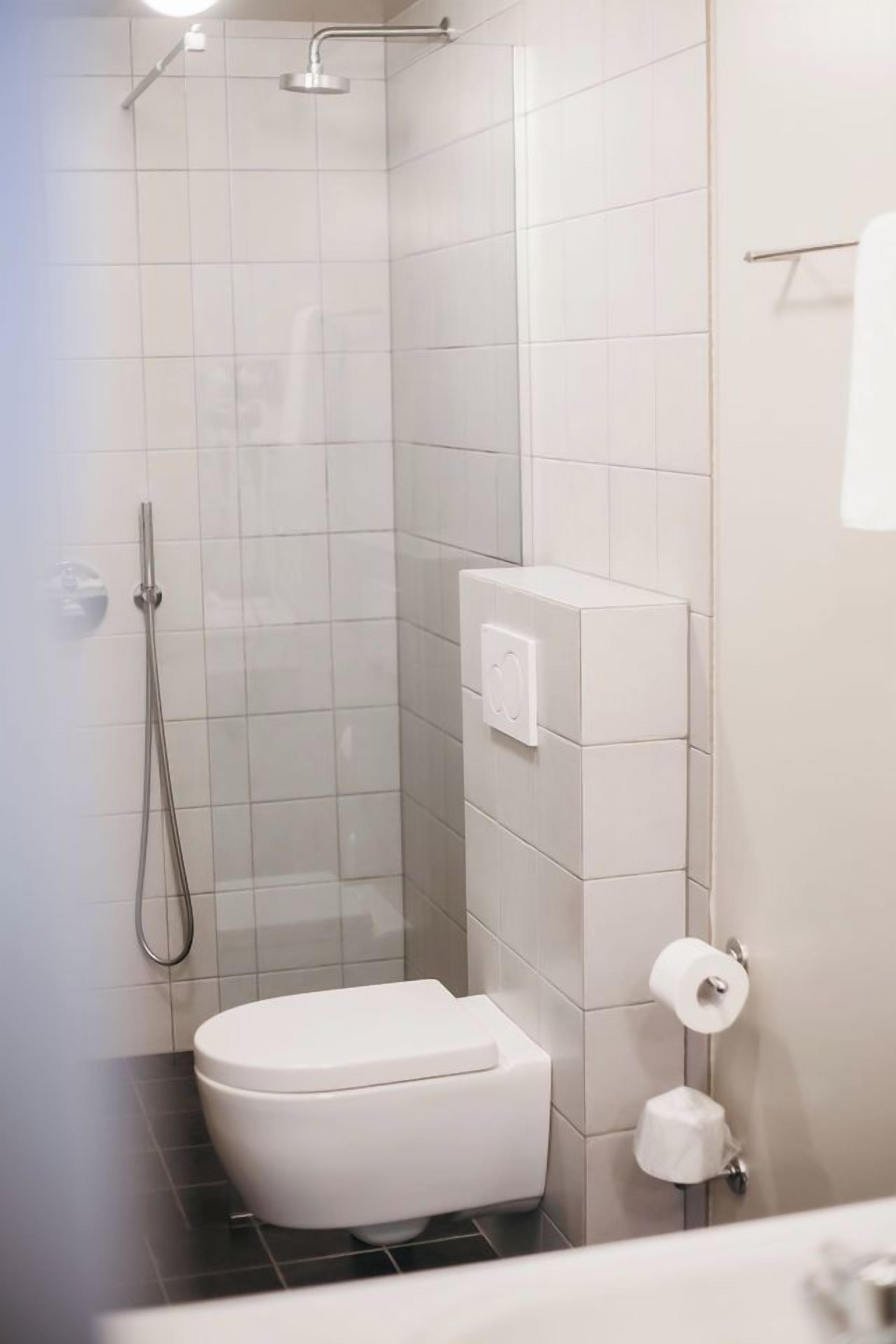 Un baño moderno con ducha, inodoro y un perchero para toallas.