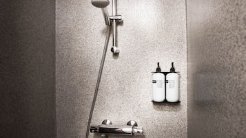 Ducha con cabezal de ducha manual, grifo empotrado en la pared y dos botellas de champú y acondicionador.