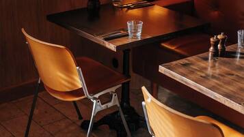 Un coin repas avec une table en bois, deux chaises, une lampe et un verre posé sur la table.