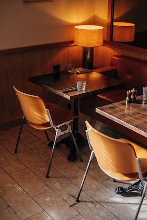 A dining area with a wooden table, two chairs, a lamp, and a glass on the table. - Hotel Höfn (Höfn)