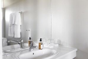 A modern bathroom with a white sink, chrome faucet, and a mirror reflecting a towel rack. - Hotel Höfn (Höfn)