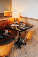 Habitación de hotel con una mesa de comedor, dos sillas, un sofá, una lámpara, una copa de vino y una botella.
