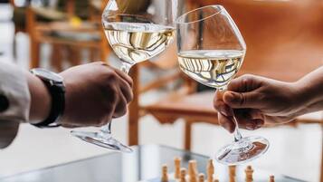 A chessboard on a glass table with two glasses of white wine.