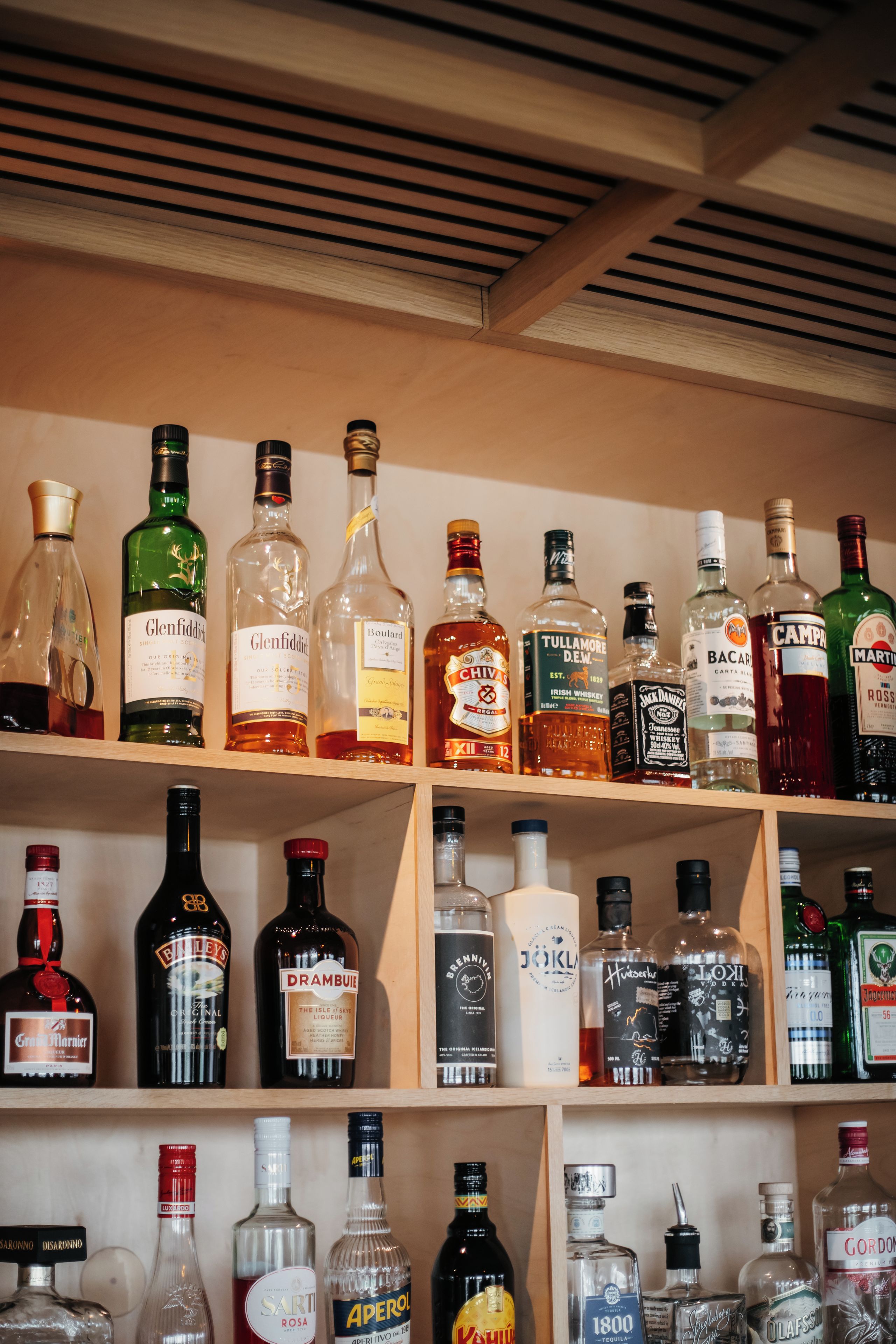 Variedad de botellas de licor dispuestas en estantes.