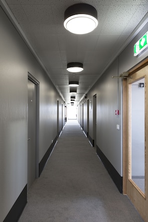 A long, narrow hallway with doors on both sides, a carpeted floor, and a ceiling with circular lights. - Hotel Höfn (Höfn)