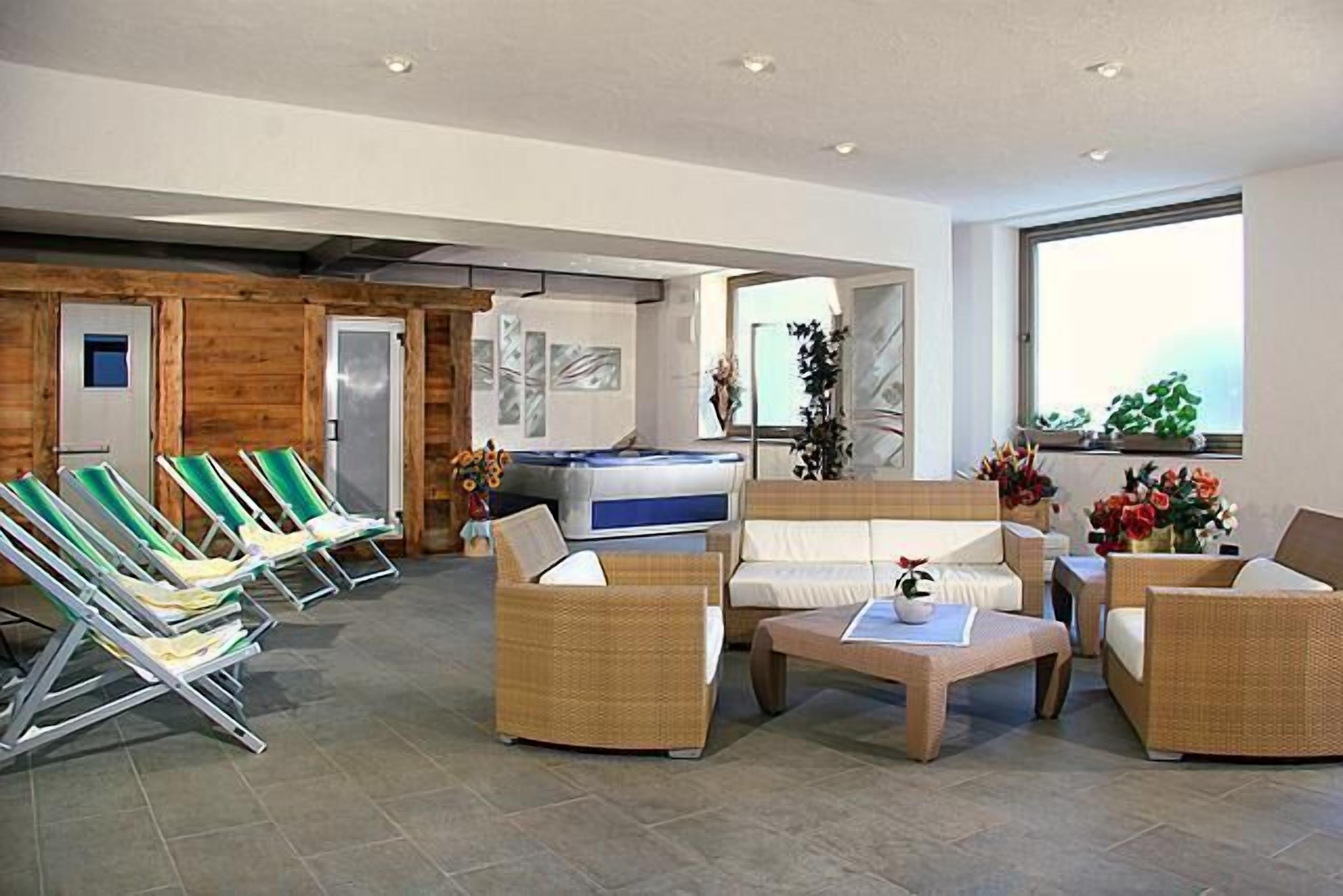 A spacious indoor area with wicker furniture, a sofa, and lounge chairs.