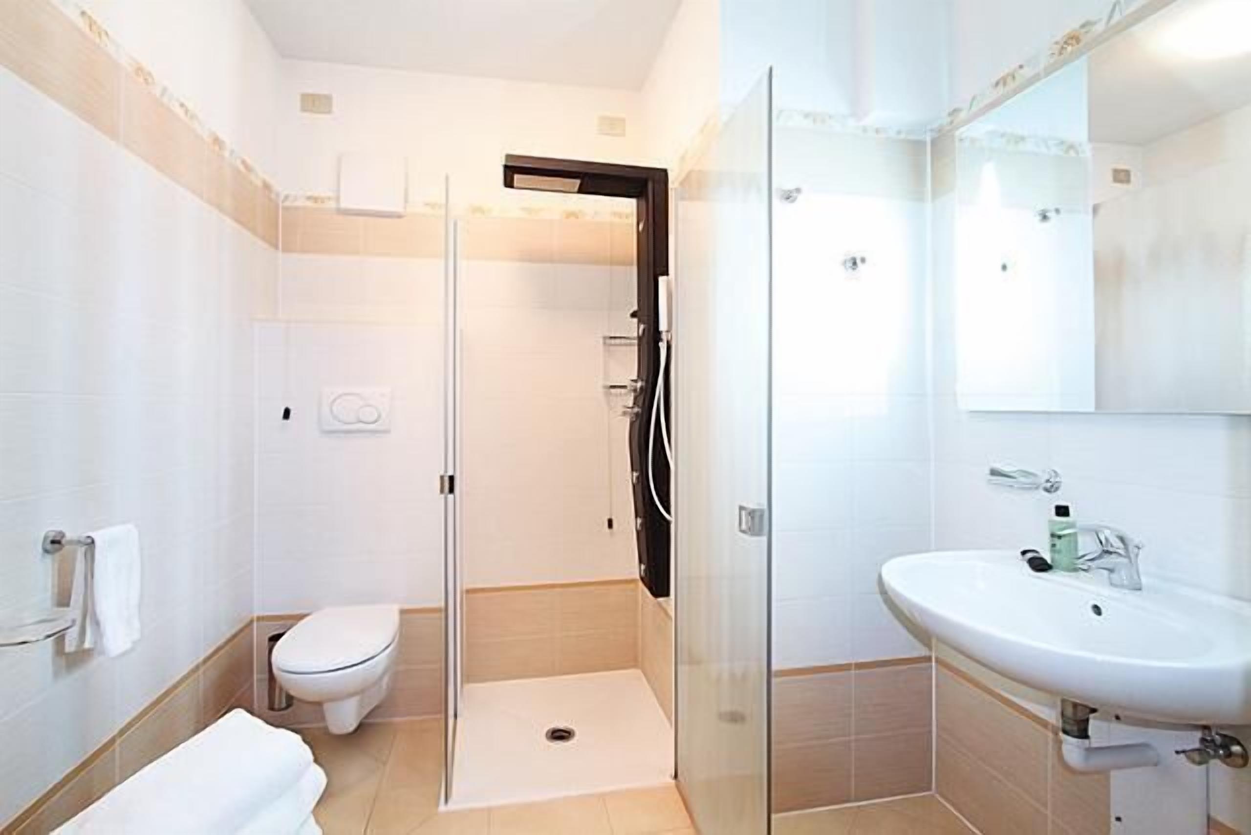 A modern bathroom with a glass shower enclosure, a toilet, and a sink with a mirror.