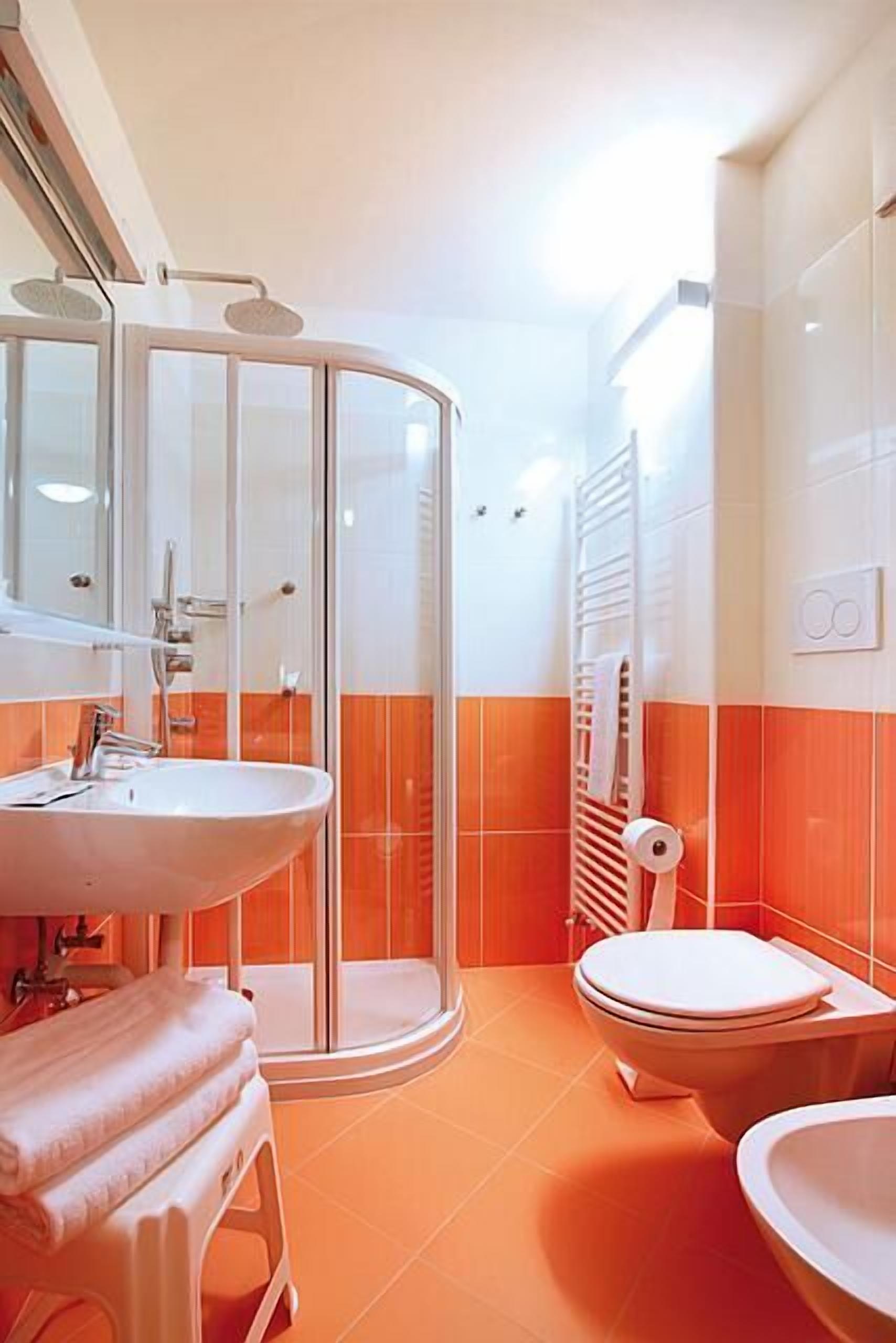 A bathroom with a glass shower enclosure, a sink, a toilet, and a towel rack.