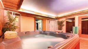 A spa area with a hot tub, wooden walls, and a plant. - Bellevue Hotel (Canazei)