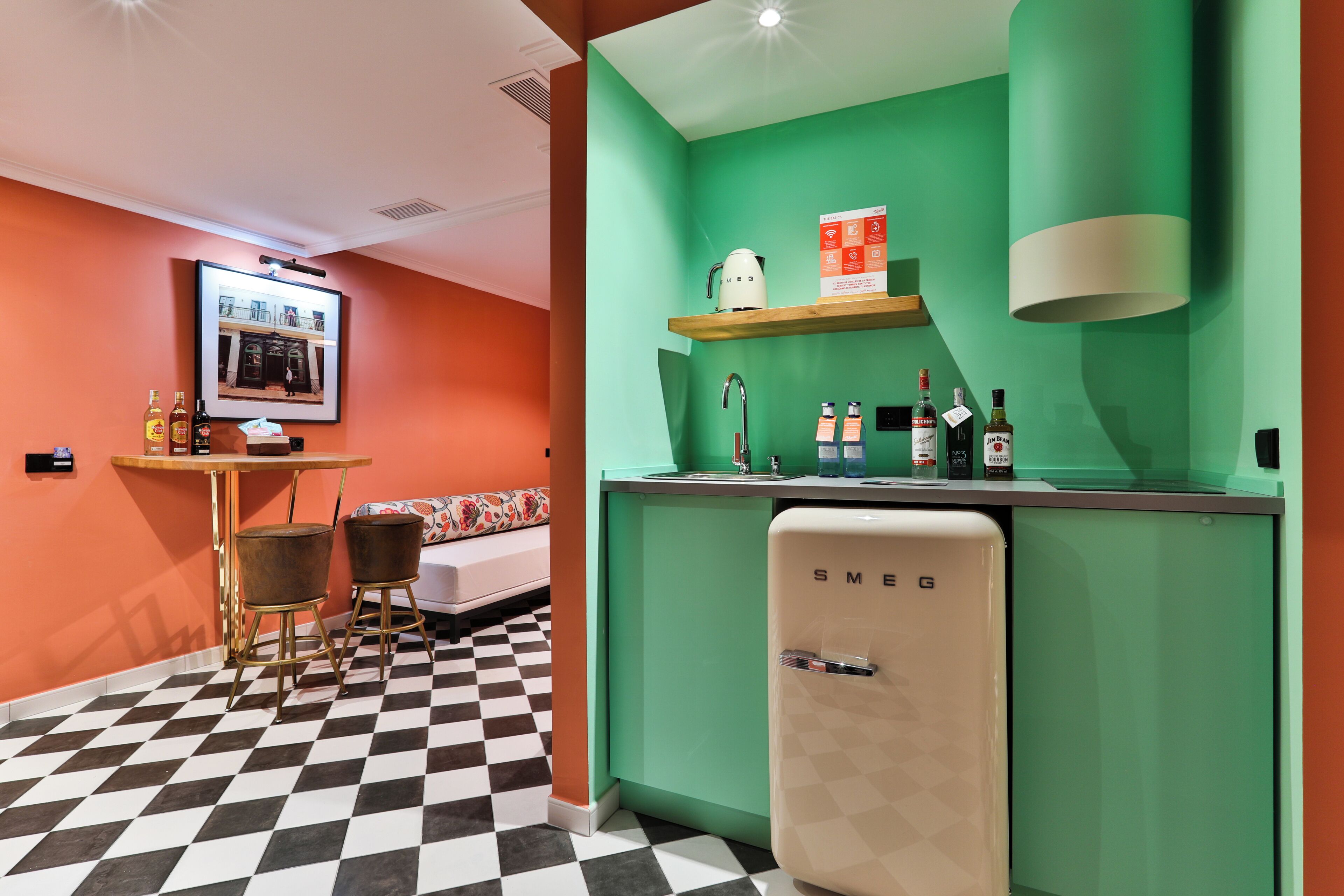 A retro-themed kitchen with a checkered floor, a vintage refrigerator, and a bar area with stools.