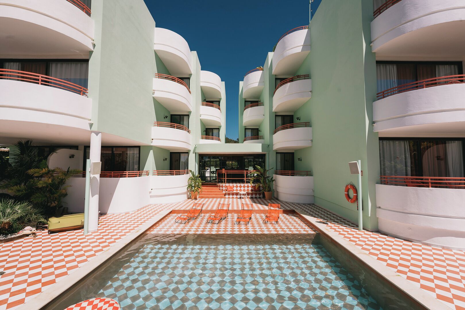 A hotel with a central pool, multiple balconies, and checkered flooring.