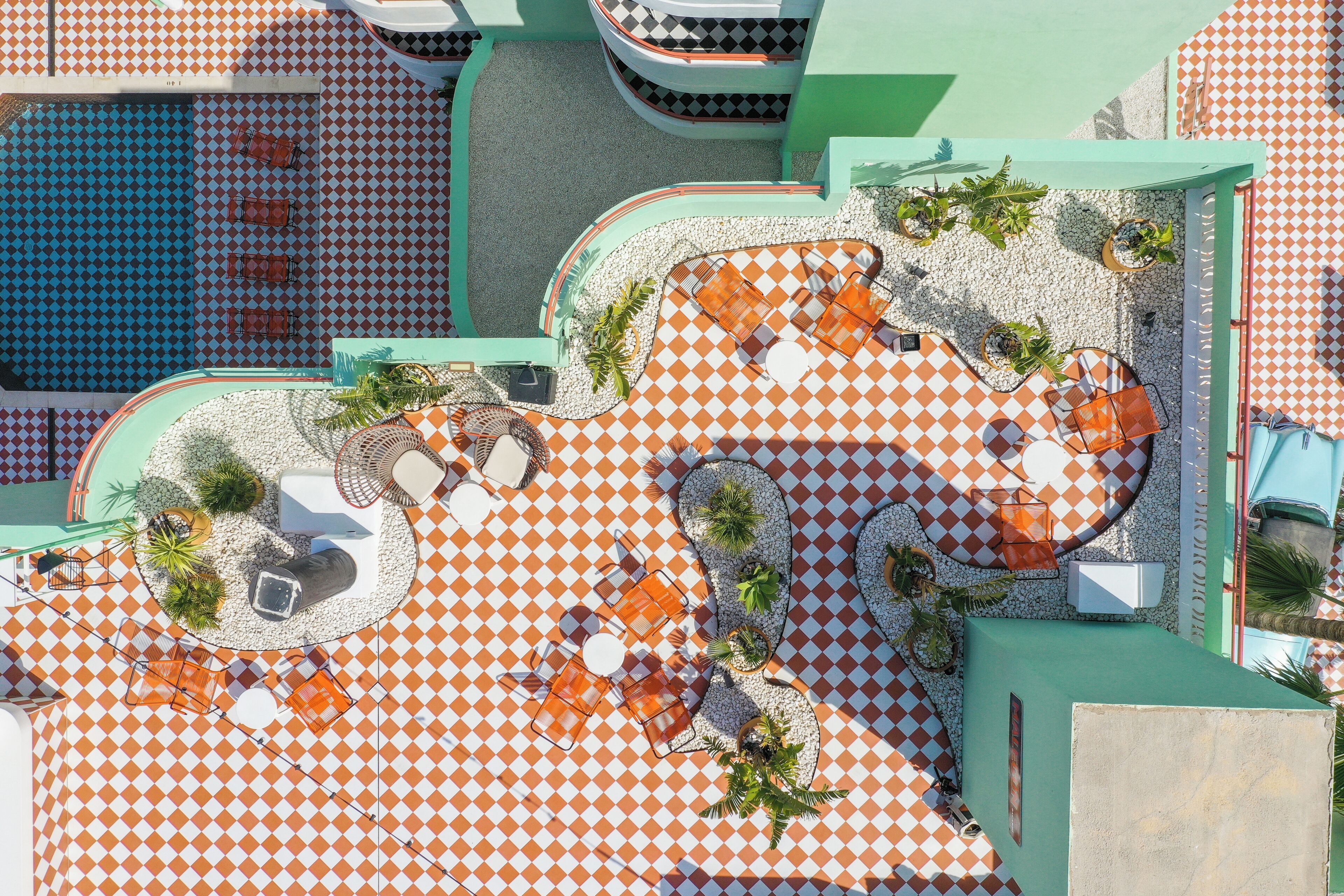 Ein Luftbild einer Dachterrasse mit Schachbrettmuster, Gartenmöbeln und Blumentöpfen.