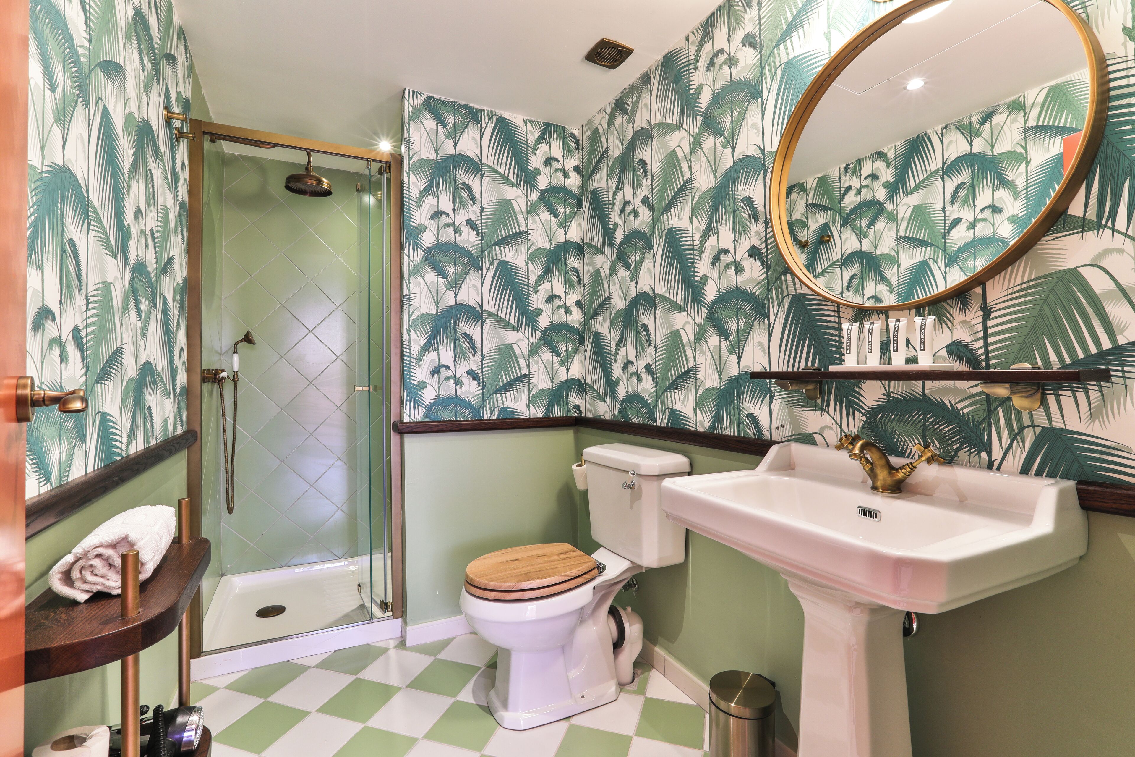 A bathroom with a shower, toilet, sink, and a mirror.