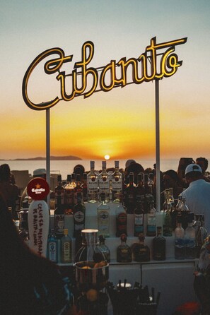 Een bar met een bord waarop 'Cubanito' staat en verschillende flessen alcohol.