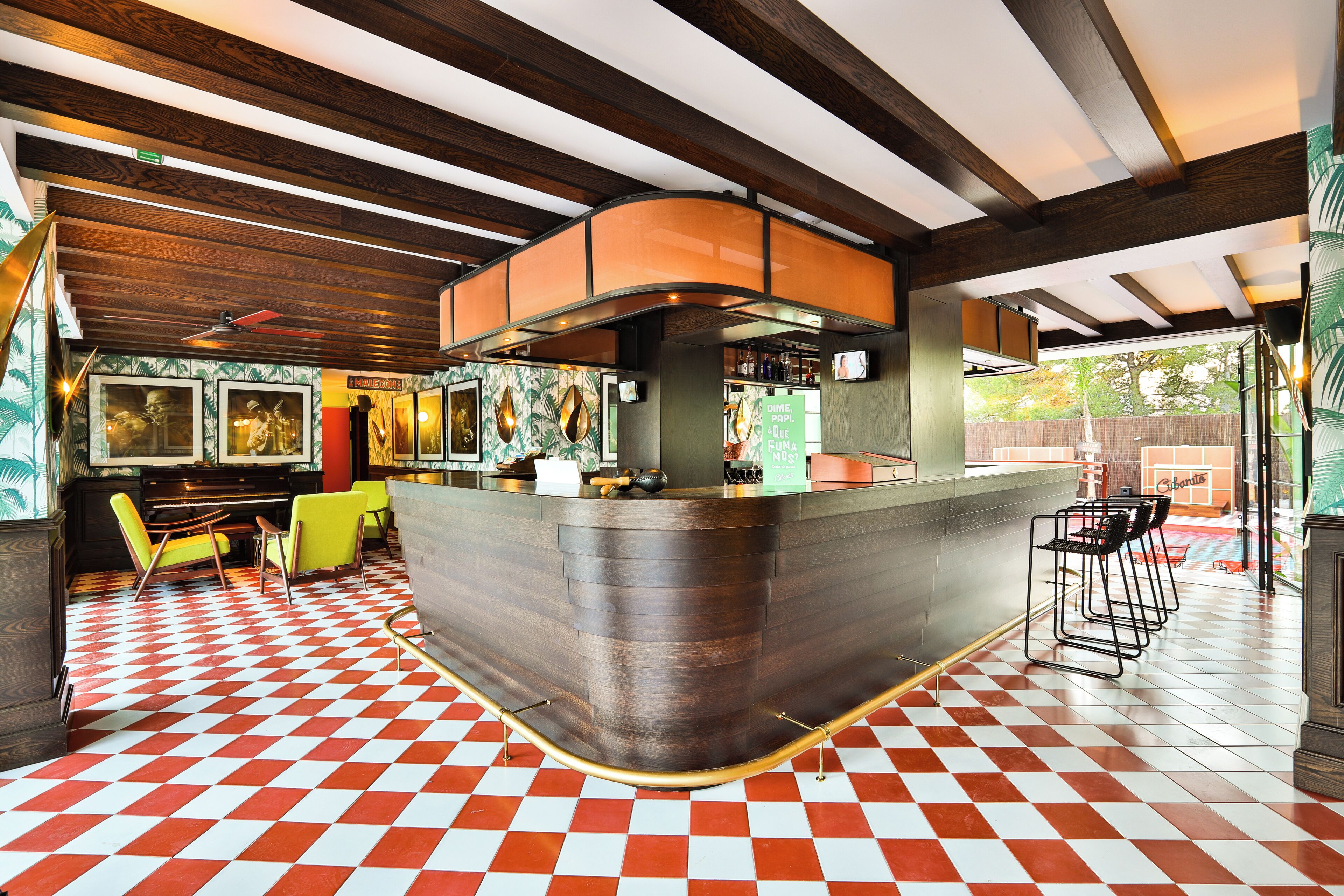 Un restaurante con piso a cuadros, vigas de madera en el techo y una zona de bar con taburetes.
