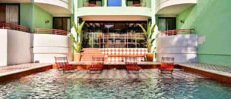 Una piscina al aire libre, sillones reclinables de piscina
