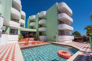 Un hôtel doté d’une piscine, de carreaux de sol à motifs géométriques et de nombreux balcons.