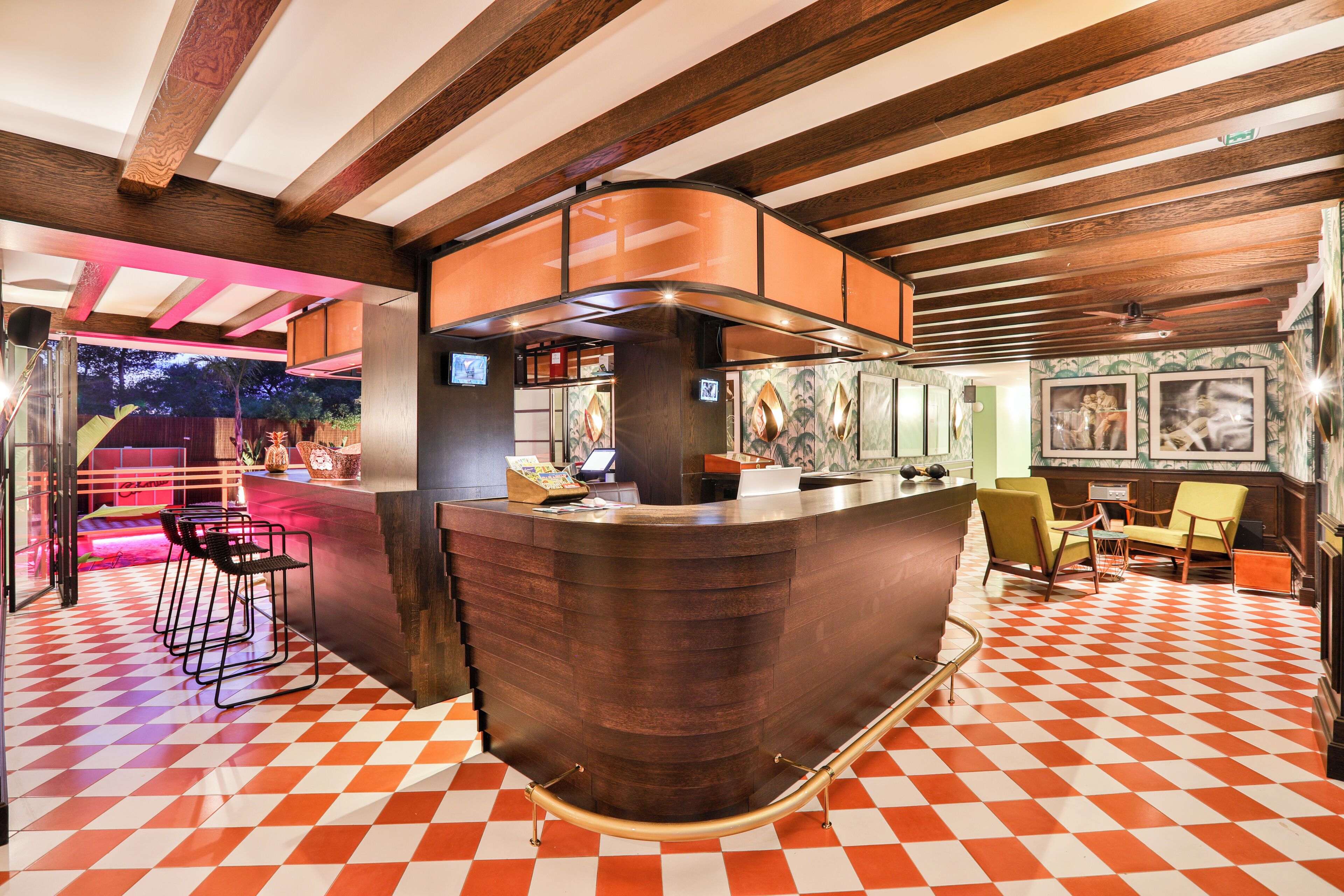 A bar area with a checkered floor, wooden beams, and bar stools.
