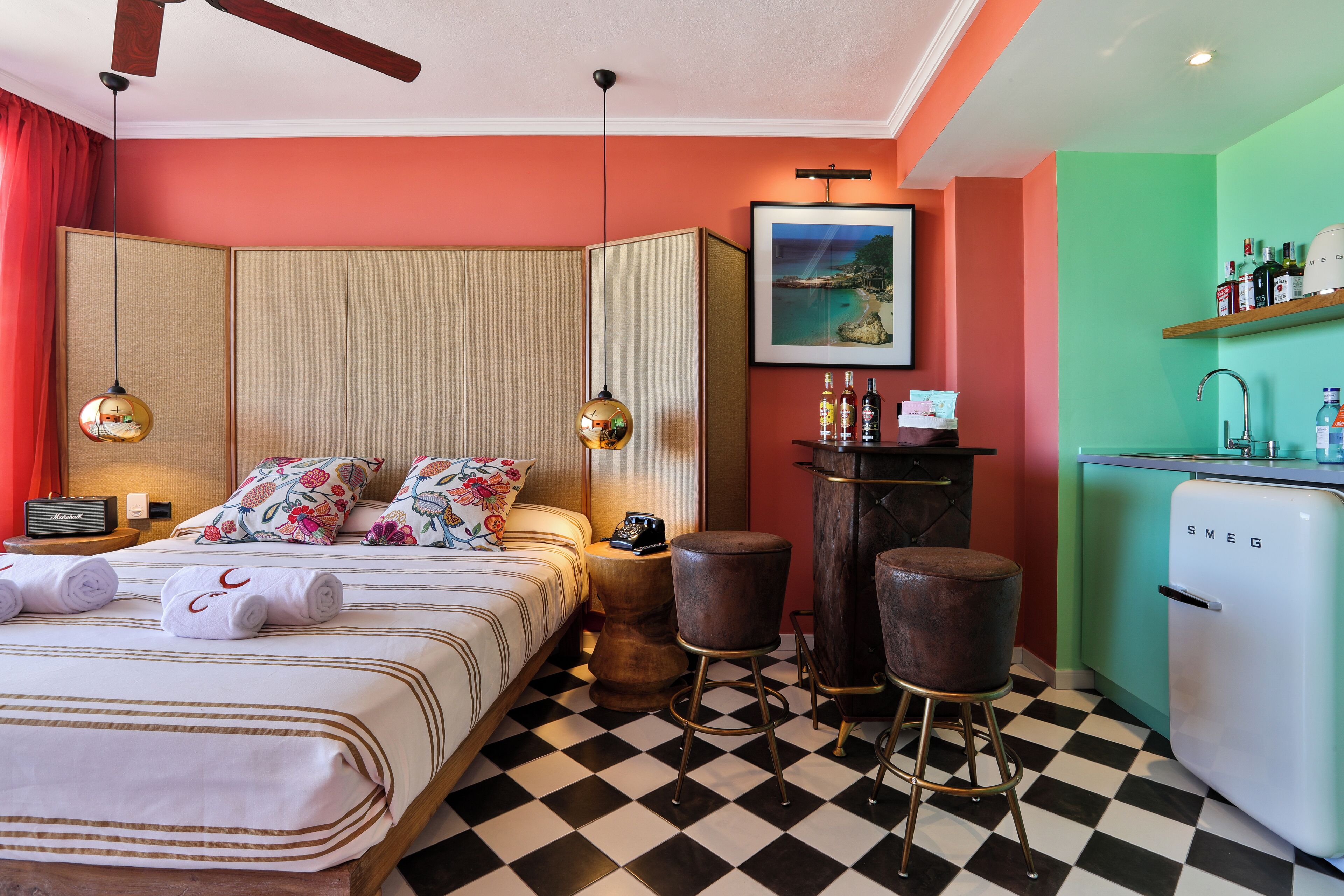A hotel room with a bed, a minibar, a bar area, and a kitchenette.