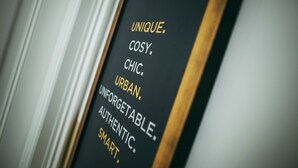 Ein Detailaufnahme eines Schildes mit den Worten 'UNIQUE. COSY. CHIC. URBAN. UNFORGETTABLE. AUTHENTIC. SMART.'