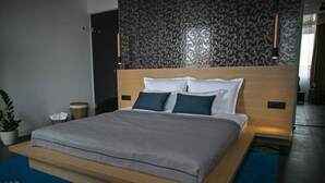 Ein modernes Schlafzimmer mit einem großen Bett, einer Wand mit dunklem Muster und einem blauen Teppich.