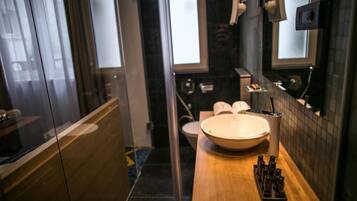 Un baño moderno con un lavamanos grande, un espejo y un inodoro.