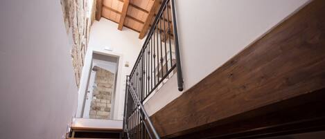 A staircase with wooden steps and black railings, leading to a door with a small window.