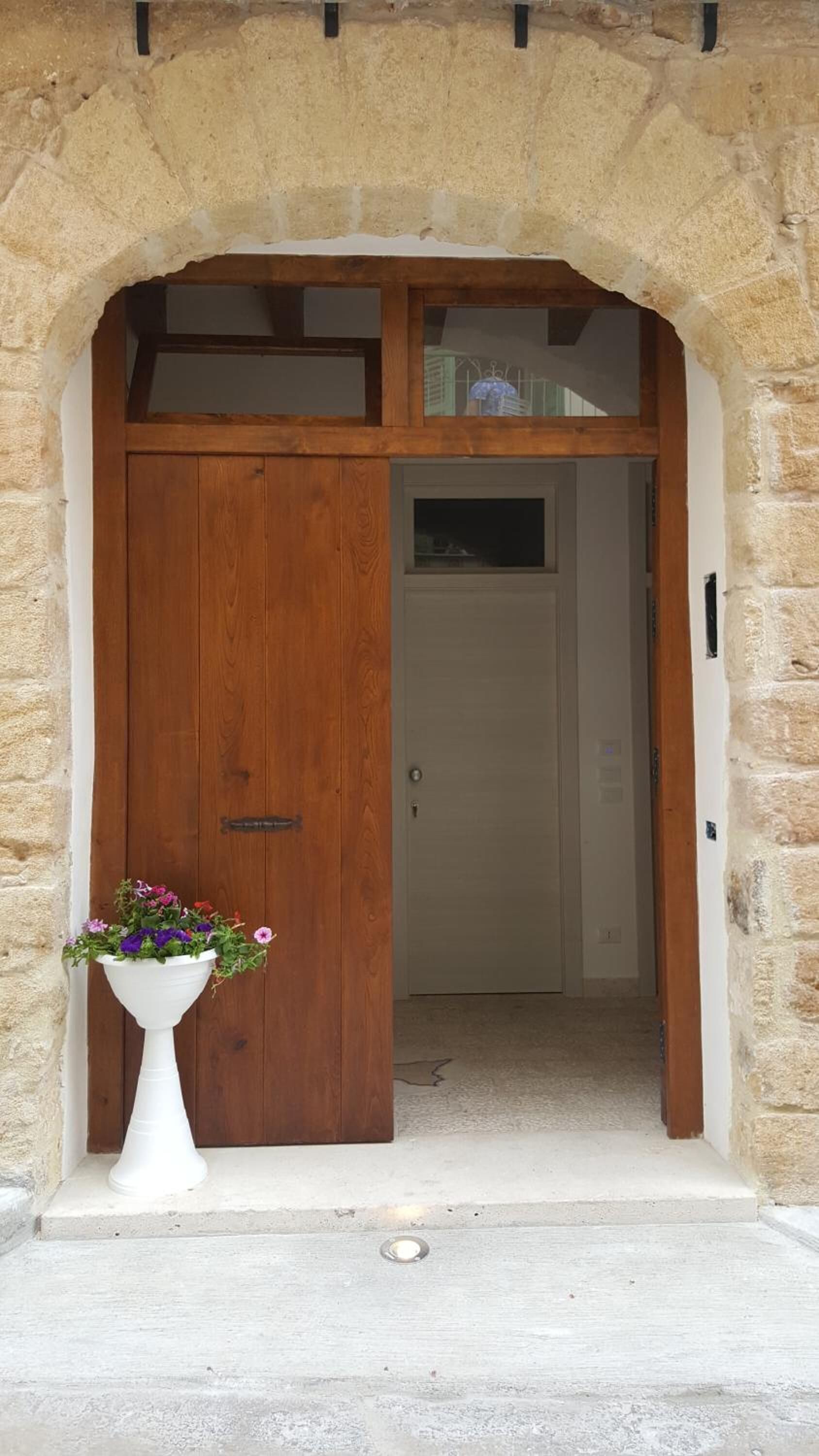 Un arc en pierre mène à une porte en bois surmontée d’une petite fenêtre.