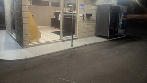 Un pequeño espacio de oficina cerrado con puerta de vidrio, una máquina expendedora y un letrero que indica una zona de oficinas.