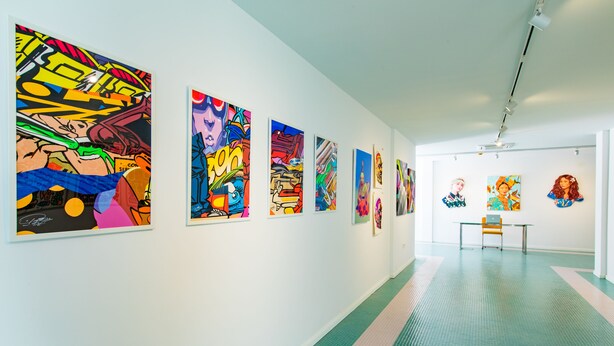 An art gallery with a long hallway displaying colorful paintings on the walls. - Paradiso Ibiza Art Hotel - Adults Only (Sant Josep de sa Talaia)