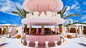 A circular bar area with a pink and white color scheme, surrounded by lounge chairs and tables. - Paradiso Ibiza Art Hotel - Adults Only (Sant Josep de sa Talaia)