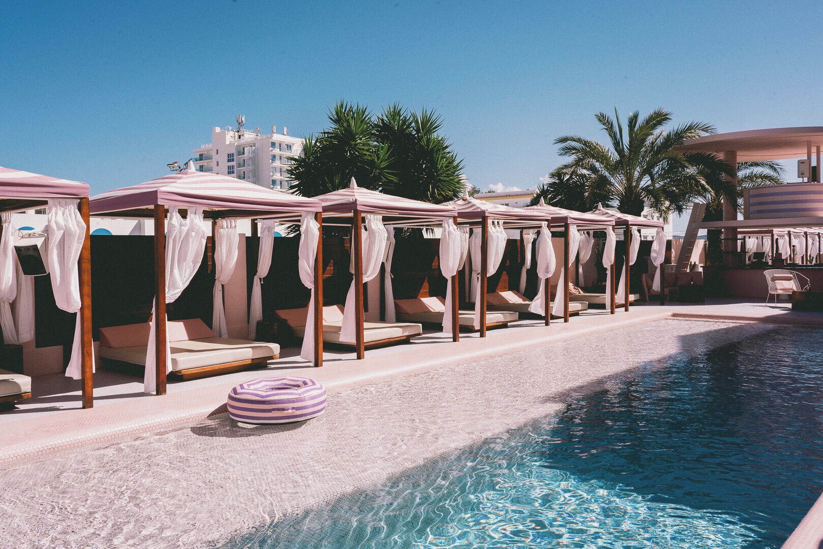A poolside area with multiple sun loungers and canopy tents.