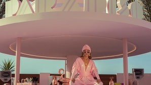 A pink, circular structure with the word "PARADISE" on it, and a person sitting on a stool in front of it. - Paradiso Ibiza Art Hotel - Adults Only (Sant Josep de sa Talaia)