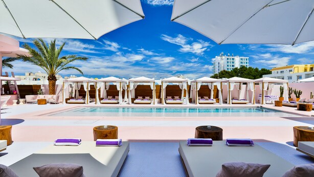 A poolside area with lounge chairs, umbrellas, and a clear view of a building in the background. - Paradiso Ibiza Art Hotel - Adults Only (Sant Josep de sa Talaia)