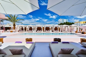A poolside area with lounge chairs, umbrellas, and a clear view of a building in the background. - Paradiso Ibiza Art Hotel - Adults Only (Sant Josep de sa Talaia)