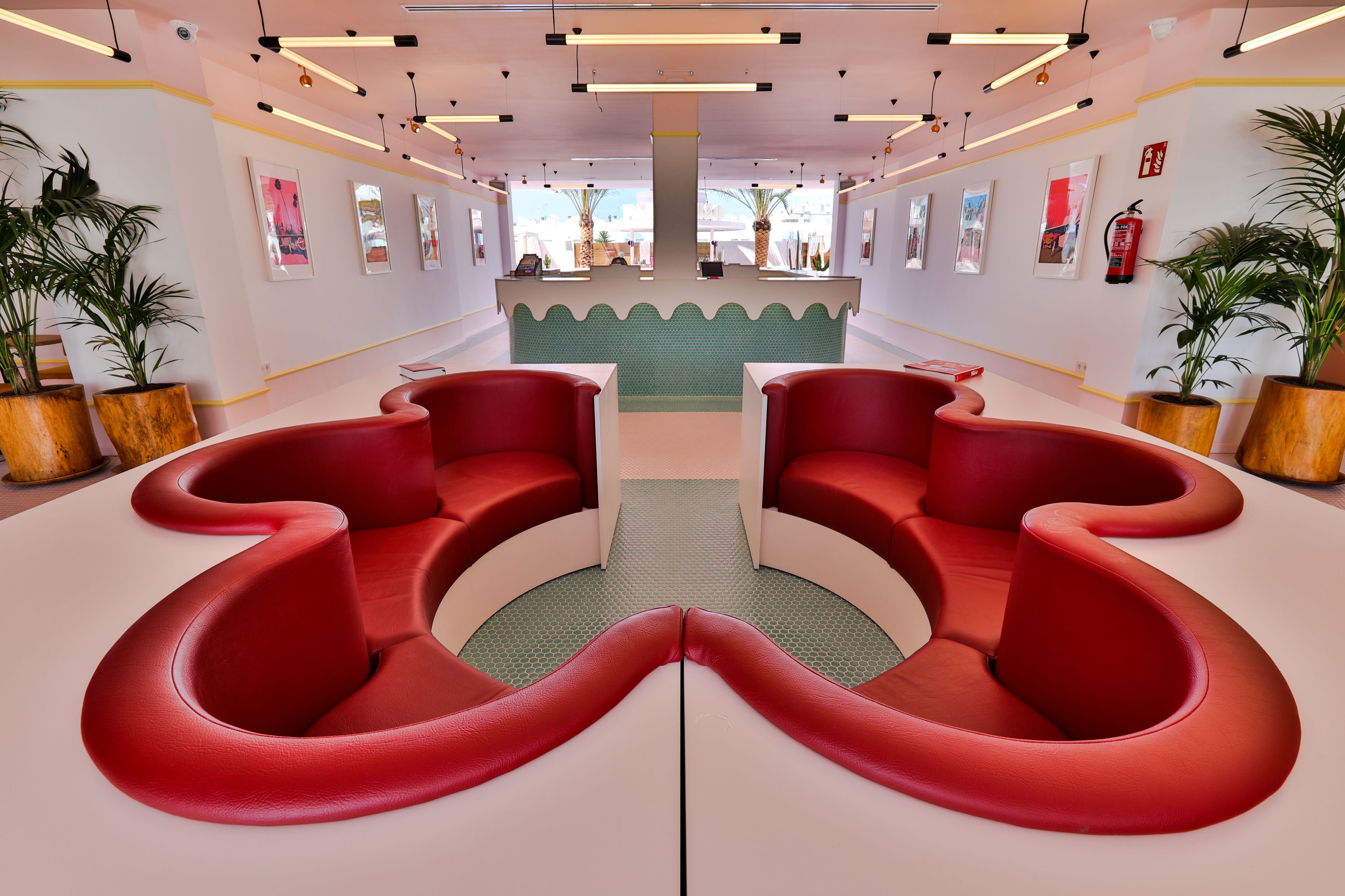 A modern lobby with red seating, a central green rug, and artwork on the walls.