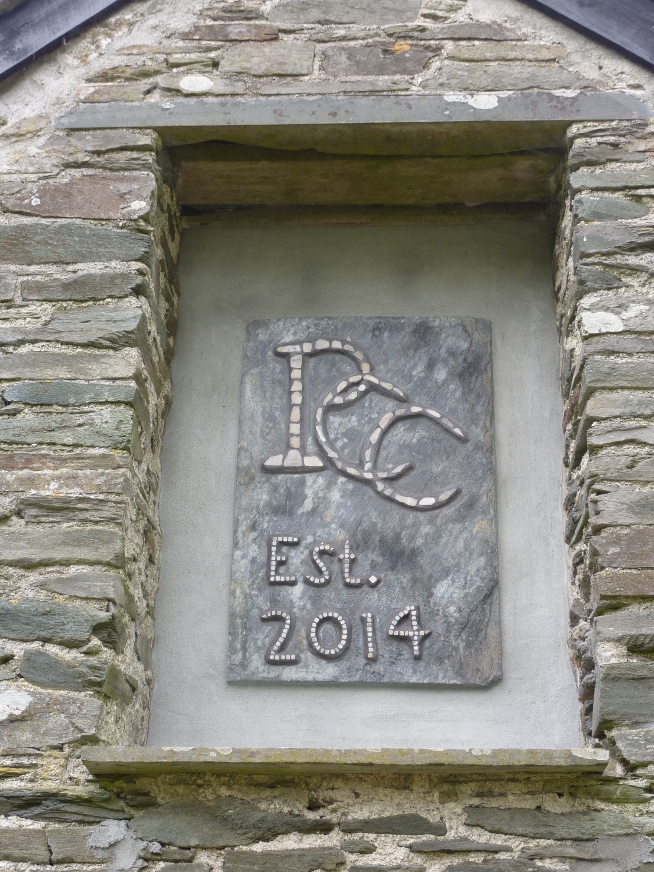 A stone plaque with a logo and establishment year.